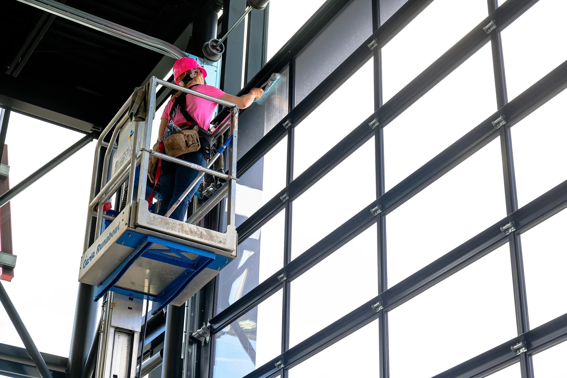 Peace Home Services cleaning a large commercial glass curtain wall from a lift in Grande Prairie
