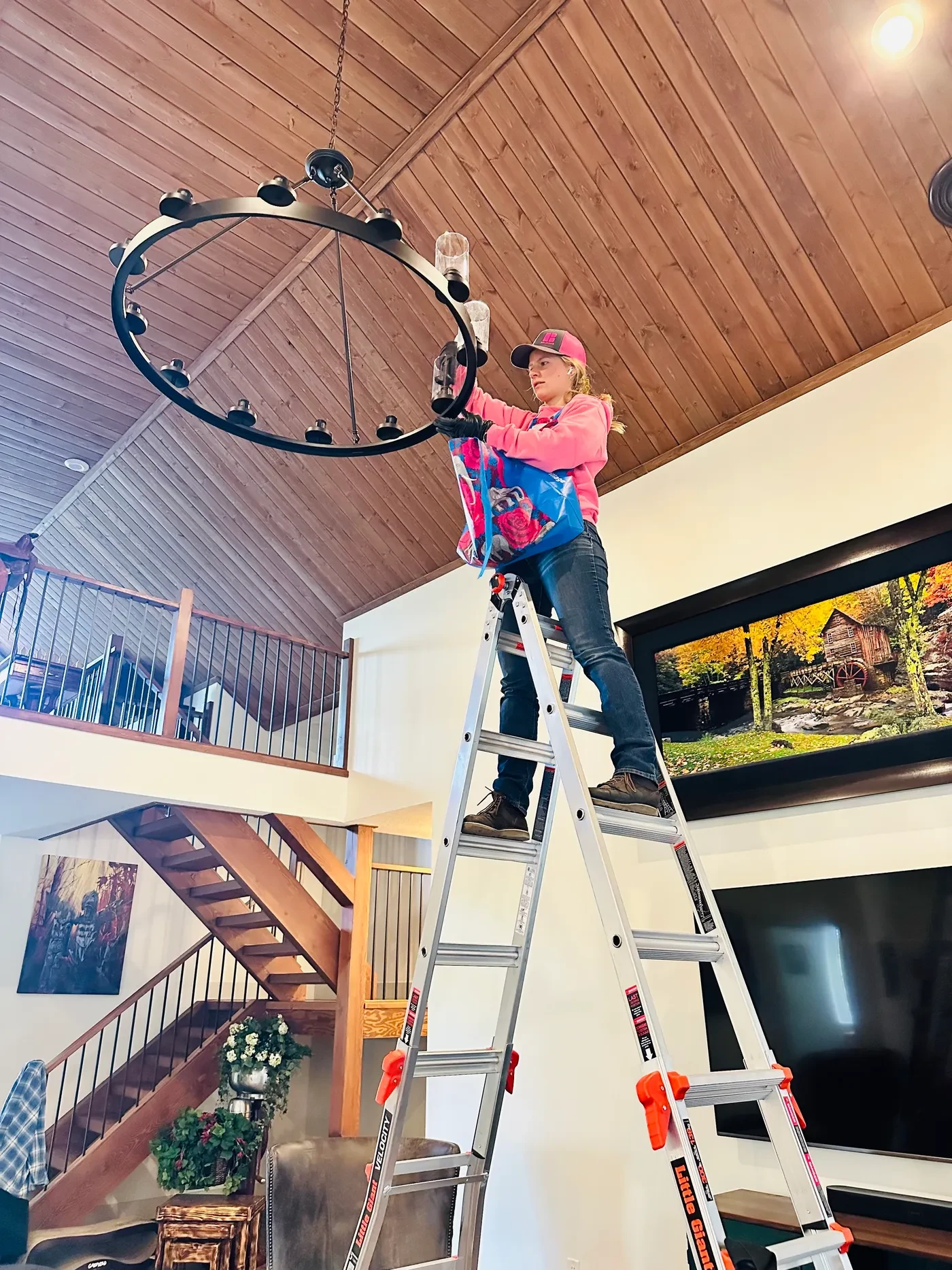 Linnae cleaning a chandelier from a ladder - attention to detail