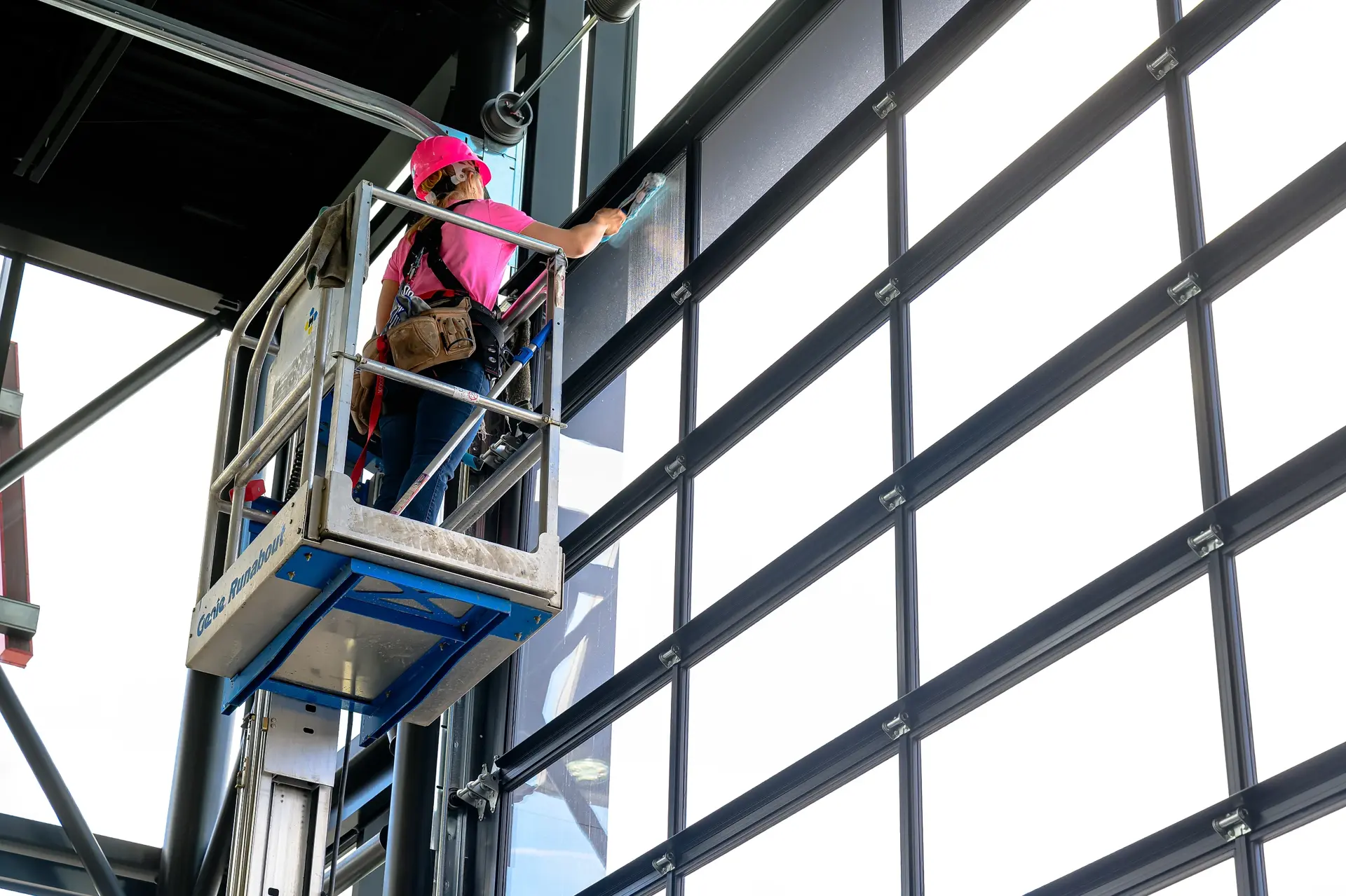 Peace Home Services cleaning a large commercial glass curtain wall from a lift